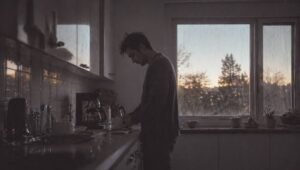Persona en la cocina durante la mañana recibiendo luz natural brillante desde una ventana, representando la activación del sistema circadiano y la energía diaria.