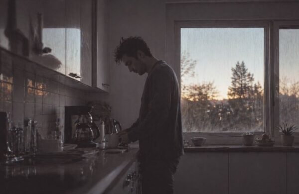 Persona en la cocina durante la mañana recibiendo luz natural brillante desde una ventana, representando la activación del sistema circadiano y la energía diaria.